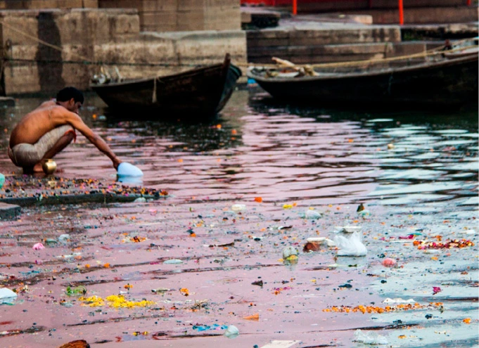 Um homem coleta água do Ganges, Varanasi, Índia