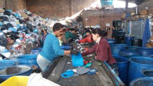 catadores-trabalhando-em-uma-linha-de-producao-de-reciclagem-separando-materiais-em-um-galpao-com-pilhas-de-lixo-ao-fundo-20250514175340-300x169 Plásticos sem reciclagem drenam renda e tempo de catadores no Rio