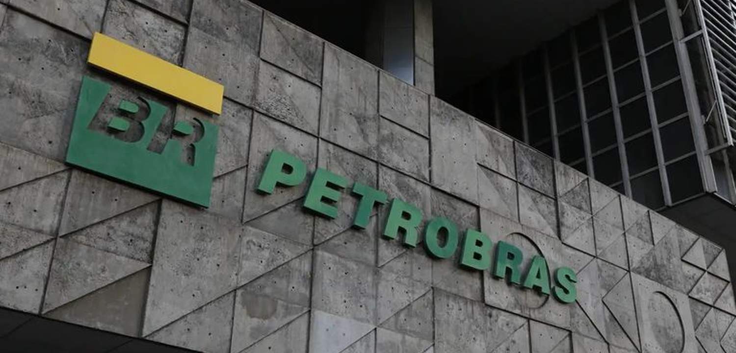 Logotipo da Petrobras em verde e amarelo, em um prédio com fachada de concreto.