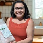 Gosto da Amazônia desembarca em Belém com pirarucu manejado Mulher sorridente segurando um pacote de pirarucu congelado da marca Gosto da Amazônia.