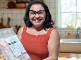Mulher sorridente segurando um pacote de pirarucu congelado da marca Gosto da Amazônia.