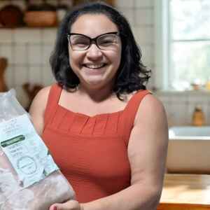 Gosto da Amazônia desembarca em Belém com pirarucu manejado Mulher sorridente segurando um pacote de pirarucu congelado da marca Gosto da Amazônia.