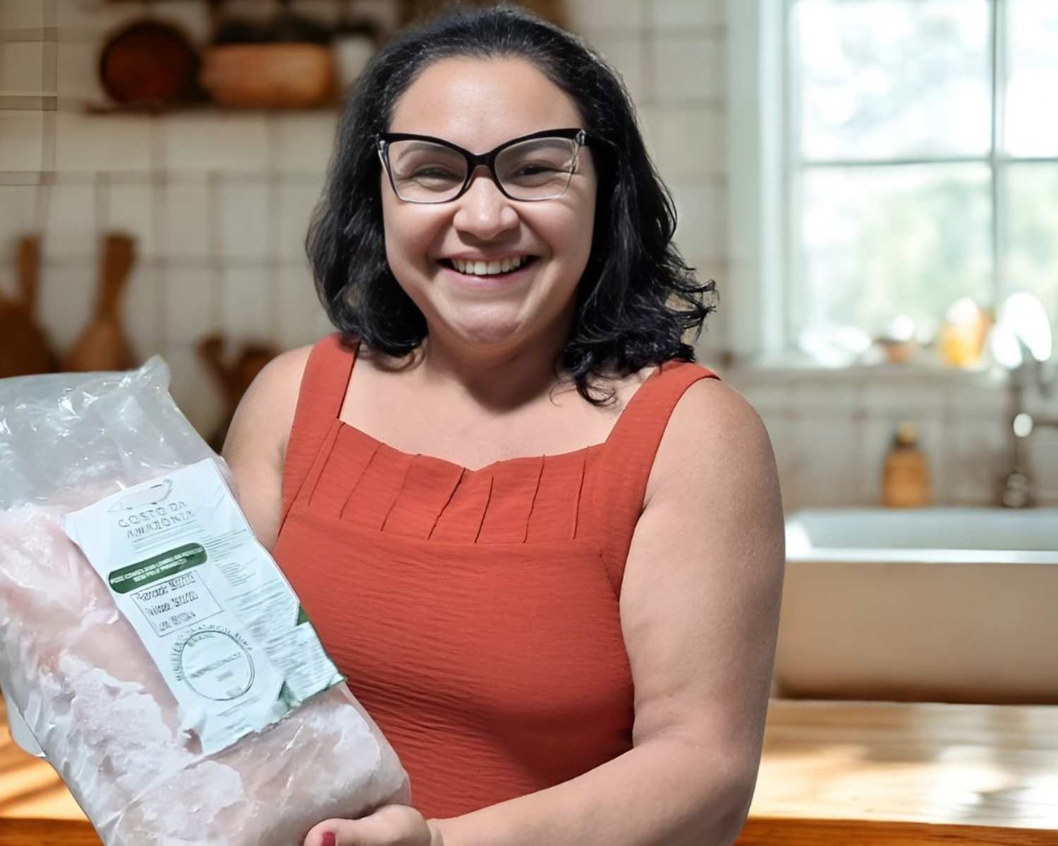 Mulher sorridente segurando um pacote de pirarucu congelado da marca Gosto da Amazônia.