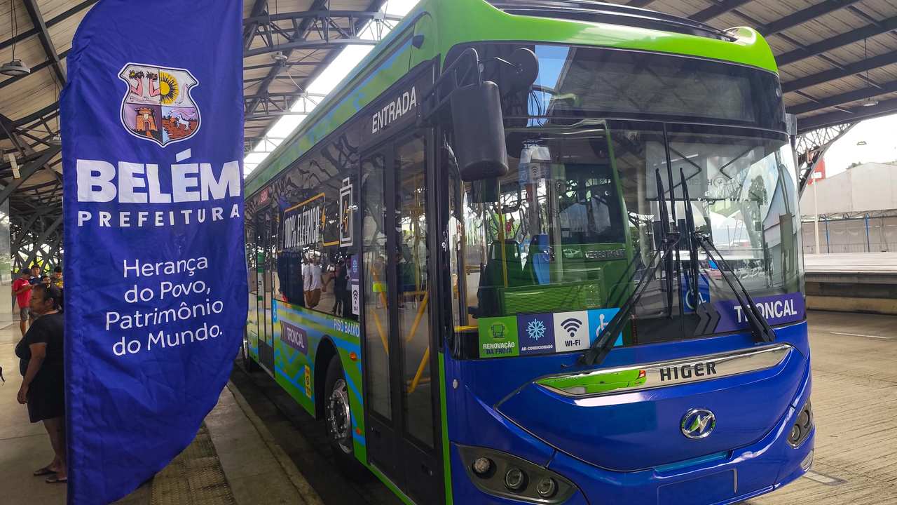 Transporte mais limpo: setor apresenta plano para cortar 68% das emissões de CO₂ até 2050 2 Ônibus elétrico verde e azul da Higer, com a inscrição 'Belém Prefeitura' em um banner ao lado, em uma parada de ônibus.