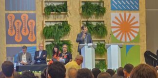 Palestrante falando em um evento sobre governança global e educação ambiental, com público presente.