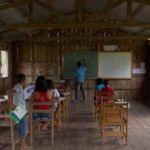 Alfabetização digital na Amazônia: projeto quer transformar comunidades ribeirinhas e indígenas por meio da tecnologia Sala de aula simples em madeira com alunos e professor, mostrando a necessidade de acesso à tecnologia em comunidades ribeirinhas.