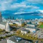 Islândia lidera ranking global de desenvolvimento humano e oferece lições ao Brasil Vista aérea de Reykjavík, Islândia, com a Igreja Hallgrímskirkja em destaque, a cidade e o oceano ao fundo.