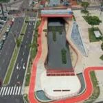 COP30: O progresso invisível da sustentabilidade Vista aérea de um parque urbano com um canal de água, áreas verdes e ciclovias, mostrando um design moderno e integrado à cidade.