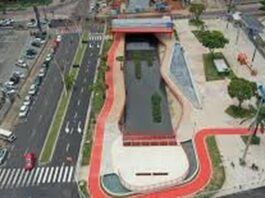 Vista aérea de um parque urbano com um canal de água, áreas verdes e ciclovias, mostrando um design moderno e integrado à cidade.