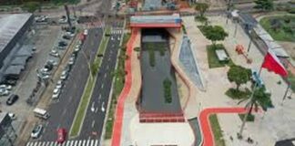Vista aérea de um parque urbano com um canal de água, áreas verdes e ciclovias, mostrando um design moderno e integrado à cidade.