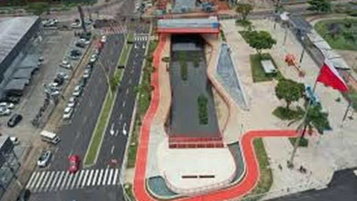 Vista aérea de um parque urbano com um canal de água, áreas verdes e ciclovias, mostrando um design moderno e integrado à cidade.