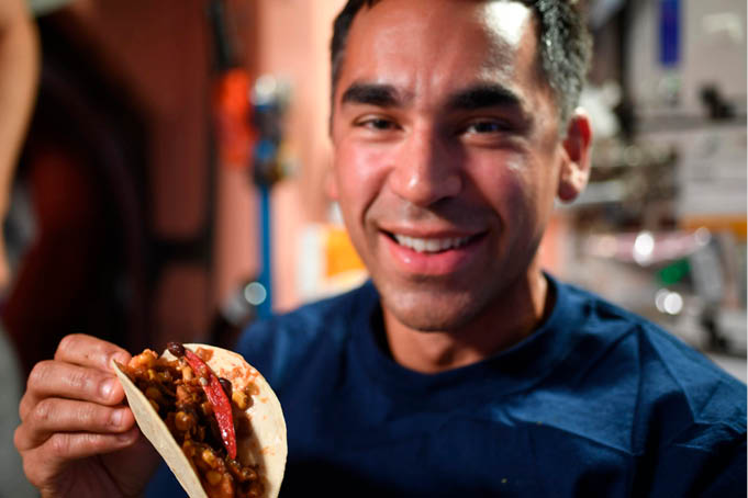 O astronauta da NASA e engenheiro de voo da Expedição 66, Raja Chari, segura um taco feito com pimentas recém-colhidas e cultivadas a bordo da Estação Espacial Internacional como parte do experimento Plant Habitat-04 (PH-04)