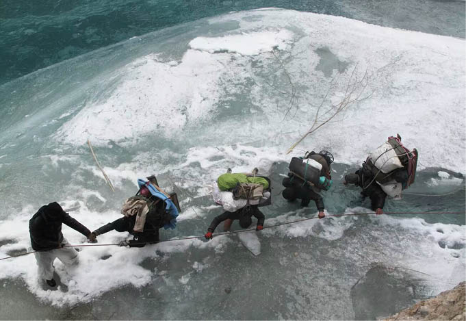 Carregadores de gelo fotografando as mudanças climáticas no rio Chadar congelado 8 Vista de cima, cinco carregadores atravessam um trecho perigoso, agarrados a uma corda