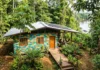 Projeto transforma plástico coletado no Tapajós em casas populares uma fachada vibrante e colorida de uma casa construída com os blocos de plástico reciclado, perfeitamente integrada ao ambiente de vegetação densa da Amazônia e com o rio ao fundo
