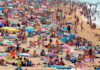 Quatro horas a mais de calor extremo, em dias quentes, causados pelas mudanças climáticas Praia lotada de banhistas e guarda-sóis em dia de calor extremo