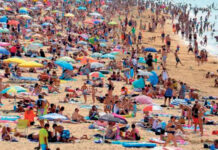 Quatro horas a mais de calor extremo, em dias quentes, causados pelas mudanças climáticas Praia lotada de banhistas e guarda-sóis em dia de calor extremo