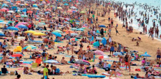 Quatro horas a mais de calor extremo, em dias quentes, causados pelas mudanças climáticas Praia lotada de banhistas e guarda-sóis em dia de calor extremo