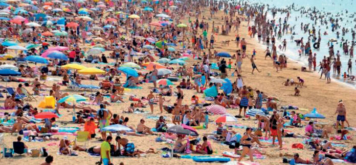 Quatro horas a mais de calor extremo, em dias quentes, causados pelas mudanças climáticas Praia lotada de banhistas e guarda-sóis em dia de calor extremo