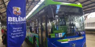 Ônibus elétrico verde e azul da Higer, com a inscrição 'Belém Prefeitura' em um banner ao lado, em uma parada de ônibus.
