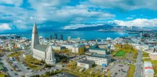 Vista aérea de Reykjavík, Islândia, com a Igreja Hallgrímskirkja em destaque, a cidade e o oceano ao fundo.