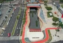 Vista aérea de um parque urbano com um canal de água, áreas verdes e ciclovias, mostrando um design moderno e integrado à cidade.