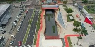 Vista aérea de um parque urbano com um canal de água, áreas verdes e ciclovias, mostrando um design moderno e integrado à cidade.